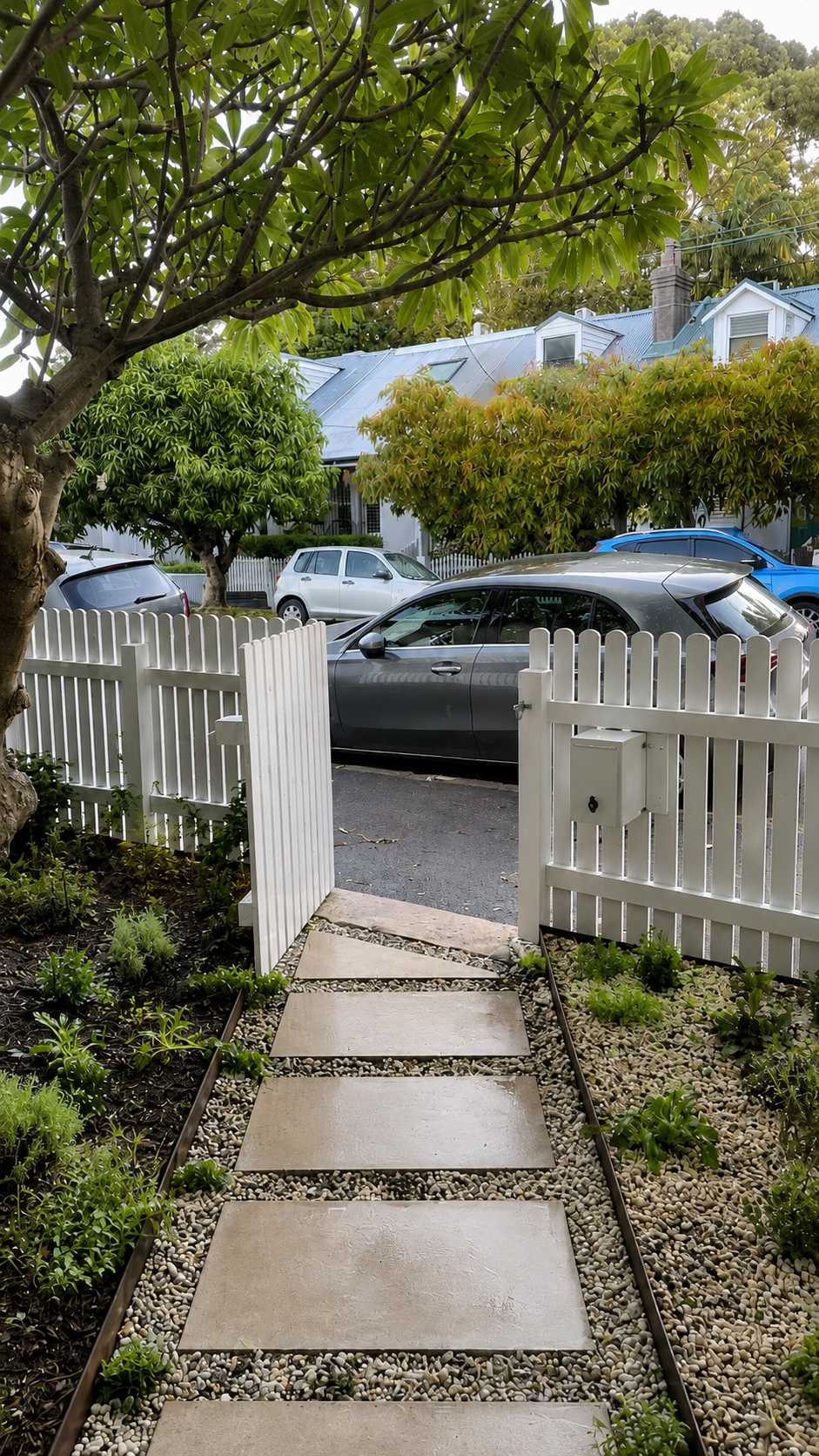 Limestone paver path through front garden with low planting and white picket gate
